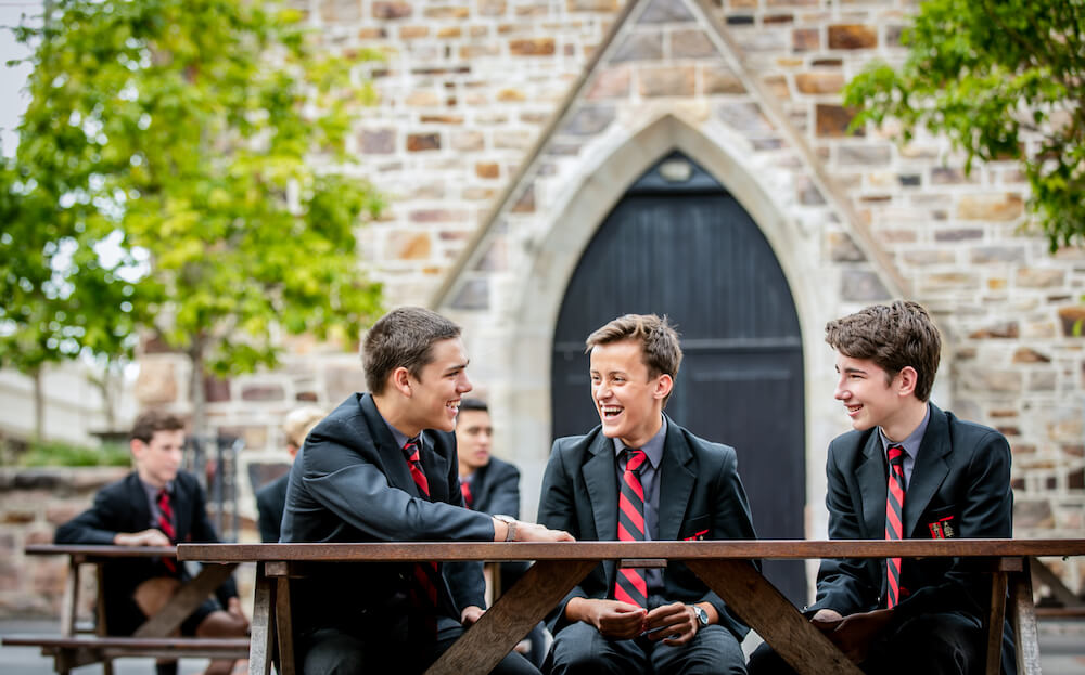 Three school students sitting and talking in front of old chapel